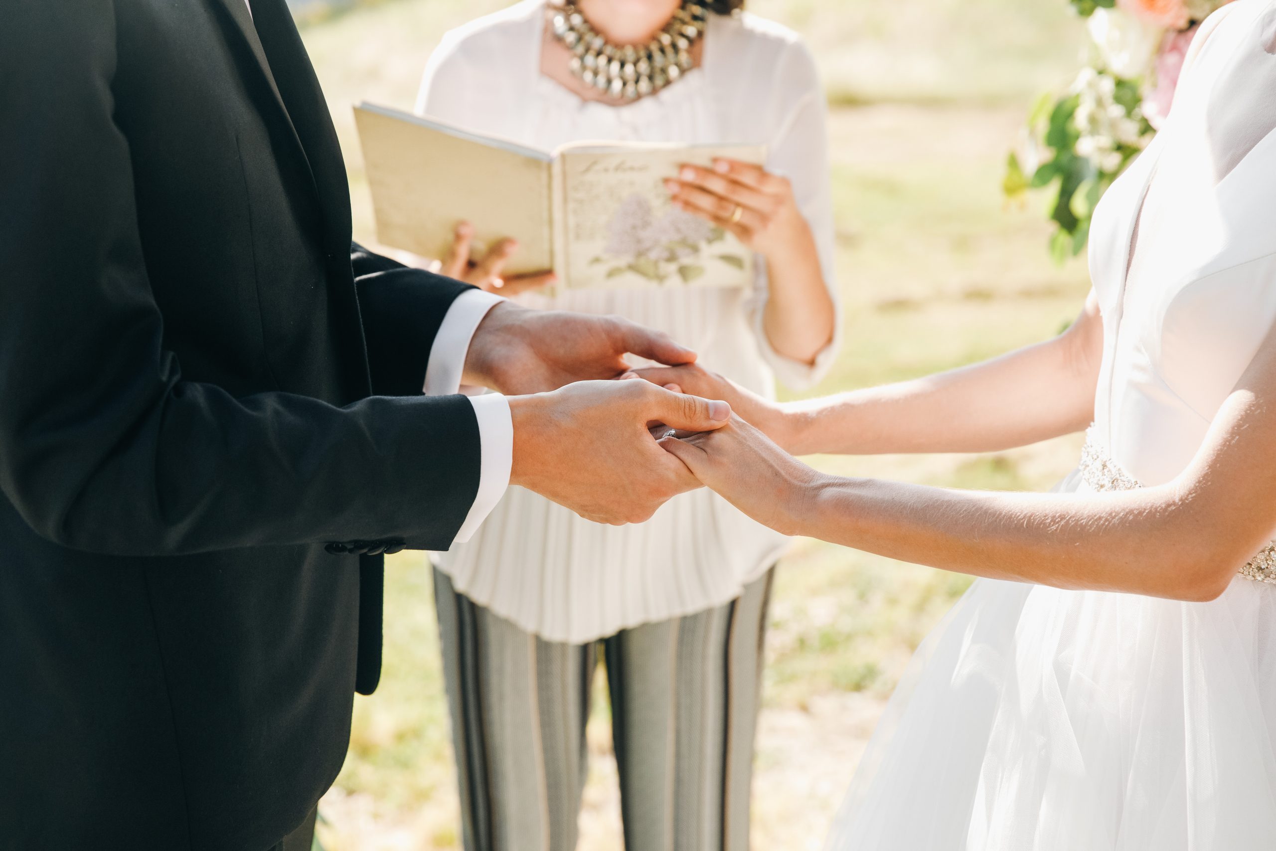 la sposa e lo sposo tengono insieme le mani durante la cerimonia scaled