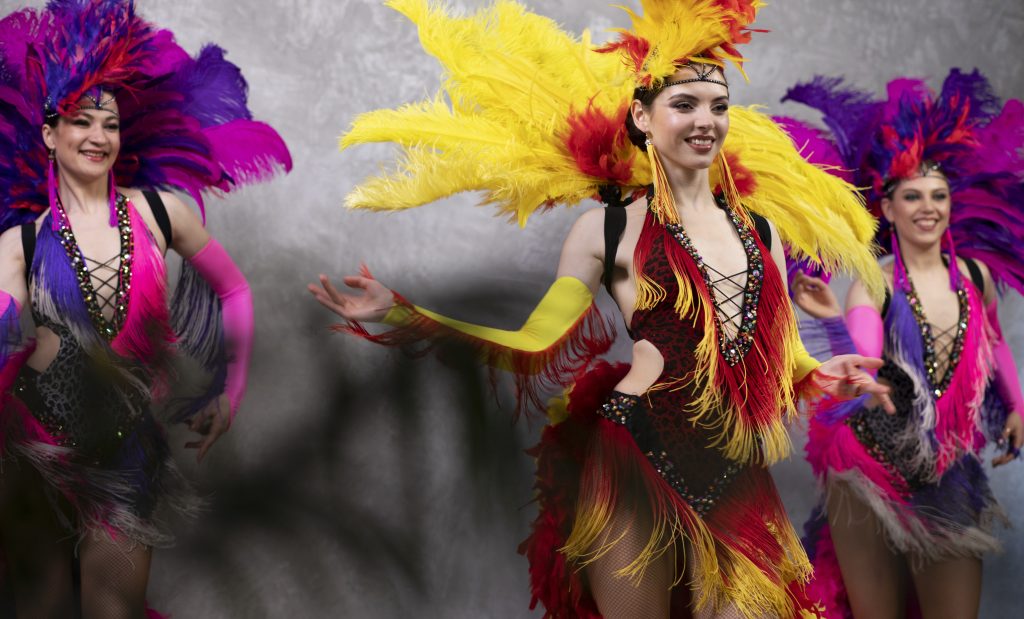 interpreti di cabaret femminili che ballano dietro le quinte in costumi di piume